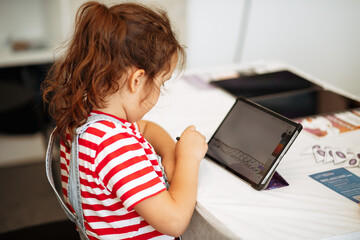 Little girl drawing on digital tablet using a digitized pen. Children's engagement of digital...