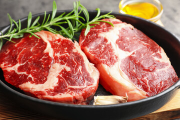 Pieces of raw beef meat and spices in baking dish on table, closeup