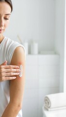 Woman applying cream to rash on her arm in bright bathroom  