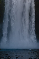 Skogafoss waterfall cascading into serene lagoon in Icelands natural landscape
