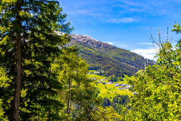 Lechtal Austria alpine mountain landscape panorama blue sky behind trees.