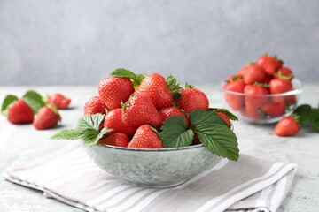 Delicious ripe strawberries and green leaves on grey table, closeup