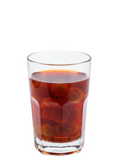 A glass cup filled with dark juice and floating fruits against a black background