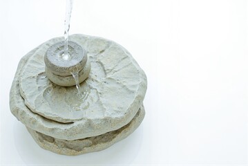 Stone water fountain with flowing water on white background  
