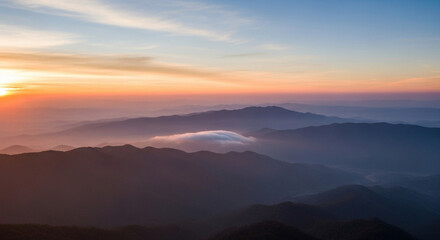 Obraz premium A cinematic aerial view of a serene sunrise over misty mountains. Layers of hills fading into the horizon with gentle clouds floating, creating a peaceful and natural atmosphere.