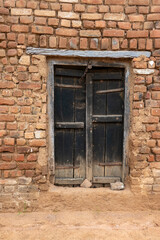 A black door in a wall in the village of Alīpura, Uttar Pradesh