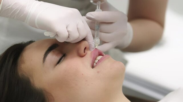 A beautician performing beauty injections on a young woman in a modern cosmetic clinic. Concept of skin rejuvenation, cosmetic procedures, and non-surgical facial enhancements for a youthful look.