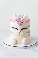 Cute birthday cake in the shape of cat with mastic ears and paws decorated with pink cream fur on the white background. Adorable cake for a little girl who likes cats