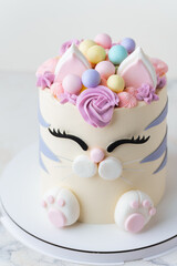 Cute birthday cake in the shape of cat with mastic ears and paws decorated with pink cream fur on the white background. Adorable cake for a little girl who likes cats