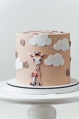 Cute African style birthday cake with beige chocolate icing decorated with edible giraffe on the white background.