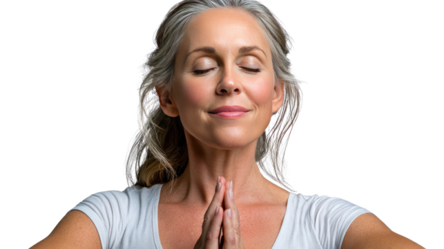 Serene Woman Meditating: A mature woman with silver hair finds inner peace during a quiet meditation session, her hands clasped in a prayer position, eyes gently closed.