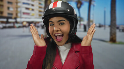 Woman lifts hands covering her eyes on street scene with young latin hispanic rider in helmet by...