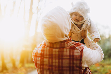 Happy father holding and playing with cute baby son in soft evening light in autumn woods. Fatherhood. Stylish man with adorable child in cozy warm sweaters having fun in fall park