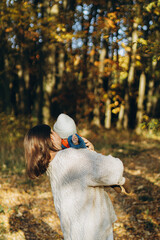 Happy mother hugging cute baby son in autumn woods. Motherhood. Stylish woman with adorable child in cozy warm sweaters embracing and relaxing in fall park
