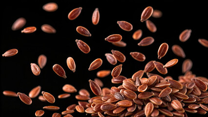 Obraz premium Flax seeds falling onto a pile against a black background in a studio shot with a macro lens