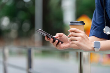 Doctor enjoying coffee while checking smartphone outdoors