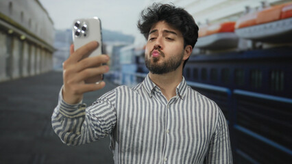 Young man with beard takes selfie on cruise ship deck, capturing his relaxed hispanic look against...