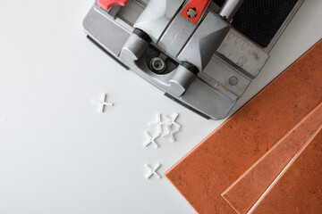 Tile cutter and tiles on white table with spacers