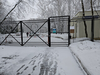 Gate is open in the snow. There is a sign on the gate that says No Parking and children medical hospice