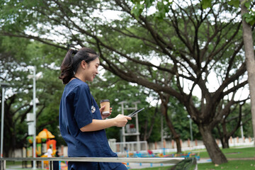 Doctor using tablet in a park while enjoying coffee