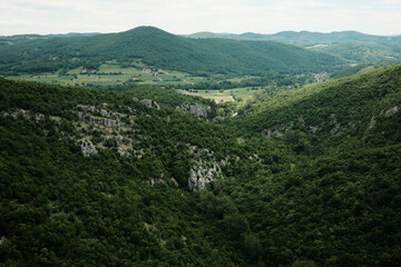 Fototapeta premium Panoramic view from above Lazarev Canyon in Serbia showing forested hills and scattered village houses in springtime. A peaceful rural contrast to the dramatic rocks nearby.