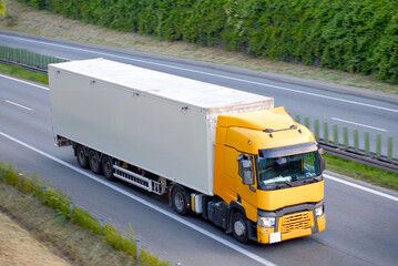 Yellow Semi Truck with Enclosed Trailer Driving on Highway