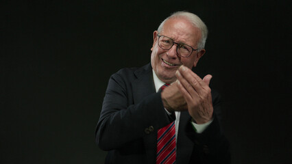 Senior man in a business suit over an isolated black background, expressing various emotions with a...