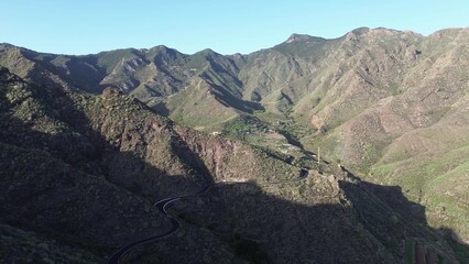Drone view of green mountain slopes on Tenerife with soft sunlight and long shadows