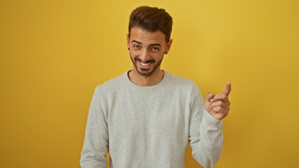 Young hispanic man smiling against isolated bright yellow background radiating charm and confidence...