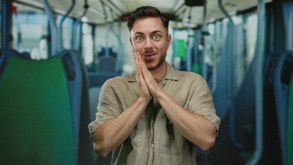 Young man with beard inside a bus expressing surprise, hands on face, in an indoor transportation...