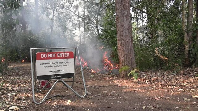 Controlled burn on Queensland's Gold Coast. Sign with fire in background.