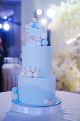 a blue three-tiered cake decorated with bear cub and caramel balls