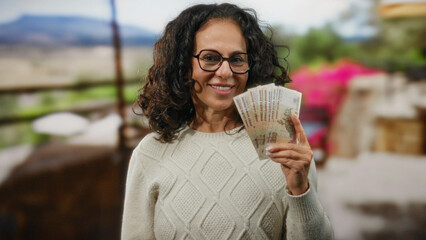 Woman holding russian rubles on a sunny restaurant terrace, suggesting financial success and...
