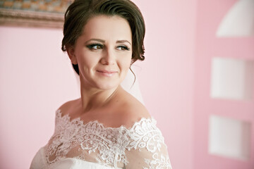 A woman in a wedding dress with a lace collar and a veil. She is smiling and looking at the camera
