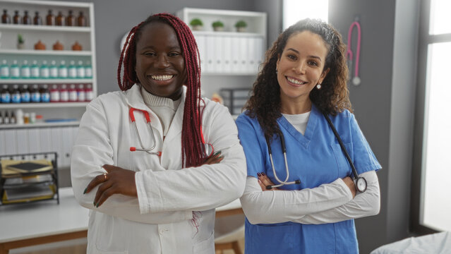 Two smiling doctors stand confidently in a hospital room, showcasing teamwork in healthcare setting, with medical equipment in the backdrop.