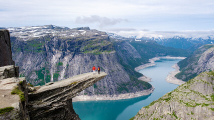 Majestic cliffside view in Norway with adventurers overlooking breathtaking fjord landscape