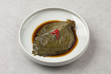   A pickled food made by soaking perilla leaves in salt water or soybean paste.
