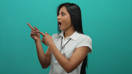 Young hispanic woman pointing with excitement against an isolated green wall, wearing a white shirt...