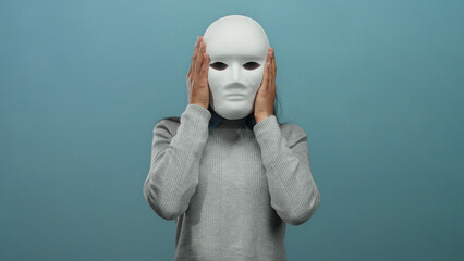 Woman holding mask smiling against blue wall showcasing emotion freedom and identity with isolated...