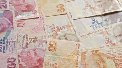Turkish banknotes scattered, featuring different denominations of lira, symbolizing financial...