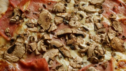 Delicious pizza topped with mushrooms and ham, showcasing a close-up view of its savory and cheesy texture