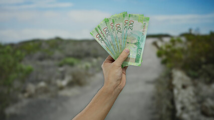Man holding russian rubles in an outdoor park setting displaying banknotes against a blurred...