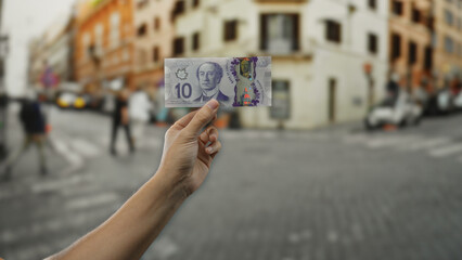 Man holding canadian banknote on a busy city street, showcasing urban financial transactions and multicultural environment in a lively outdoor setting.