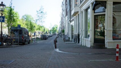 Blurred street view in amsterdam with bokeh effect showcasing defocused urban scene and canal setting on a sunny day in the netherlands with typical architecture.