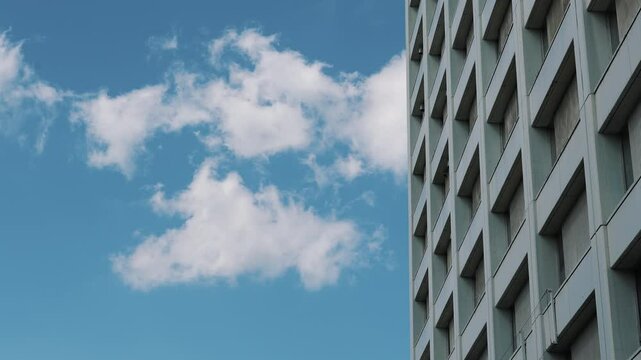 Modern corporate office building with blue sky reflection and glass skyscraper facade.