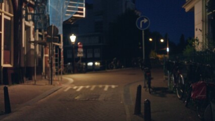 Fototapeta premium Blurry night scene in a european city with bokeh lights, deserted street, and bicycles resting quietly, evoking a serene yet mysterious urban atmosphere.