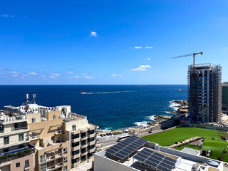 A scenic coastal view of modern buildings and solar panels with the Mediterranean