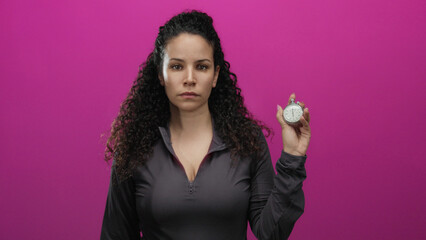 Woman holding stopwatch against pink background in isolation suggesting time management and focus...