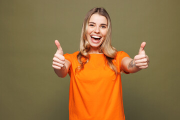 Young smiling happy Caucasian woman she wears orange t-shirt casual clothes looking camera showing...