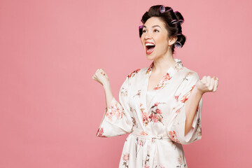 Side view young housewife housekeeper woman she wear white robe hair rollers do winner gesture...